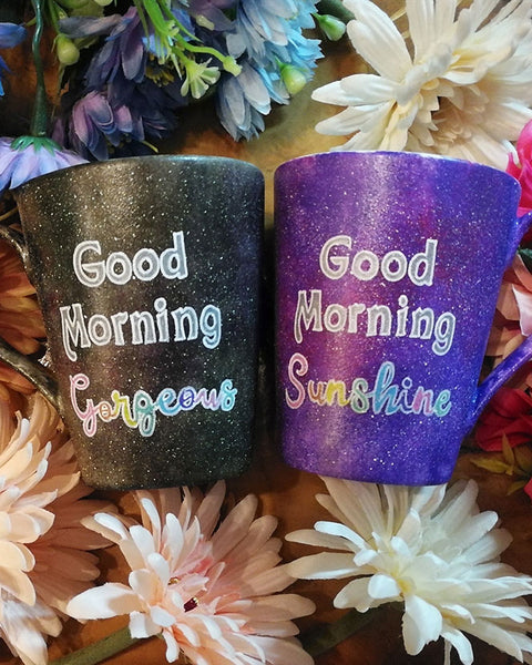 two hand-painted mugs, one in purple galaxy color  and the words "good morning sunshine" and the other in black galaxy color with the words "good morning gorgeous"