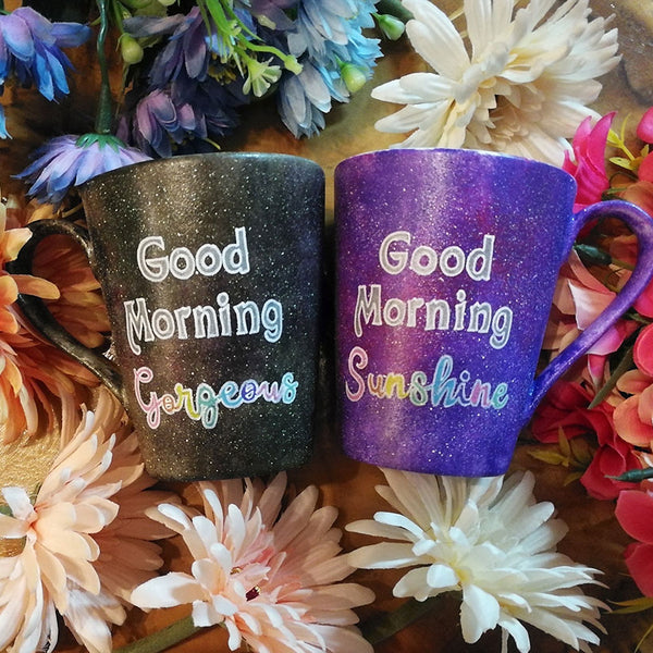 two hand-painted mugs, one in purple galaxy color  and the words "good morning sunshine" and the other in black galaxy color with the words "good morning gorgeous"