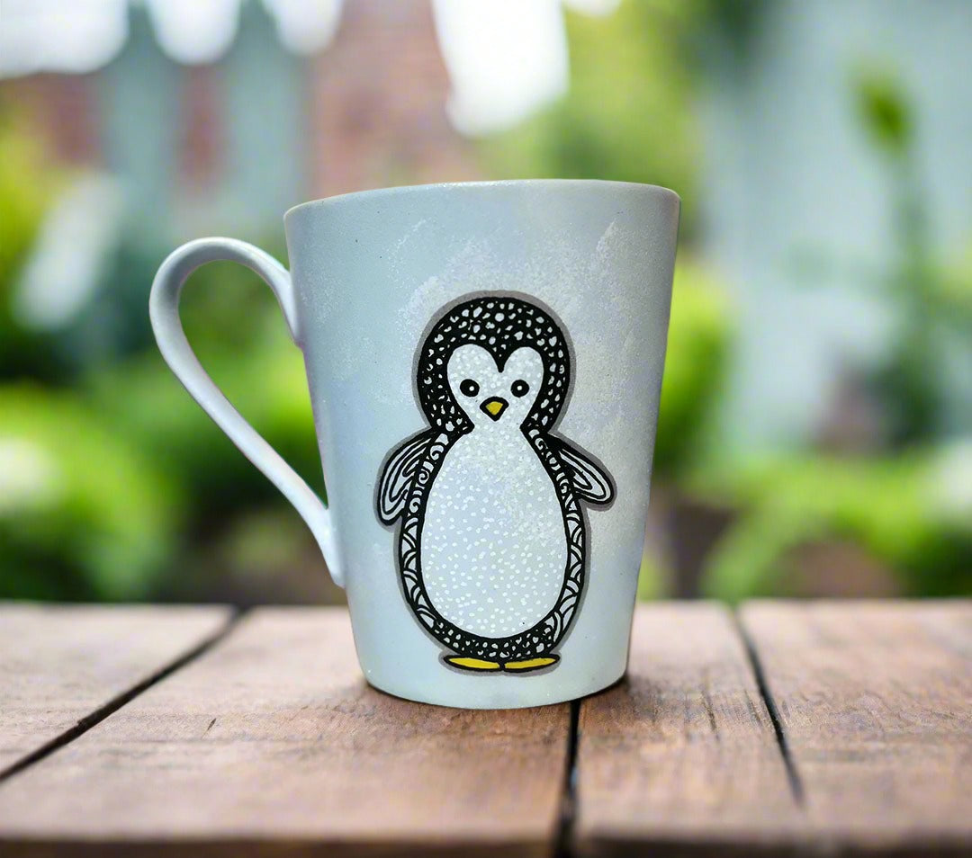 A baby blue hand painted mug with a zentangle baby penguin painted