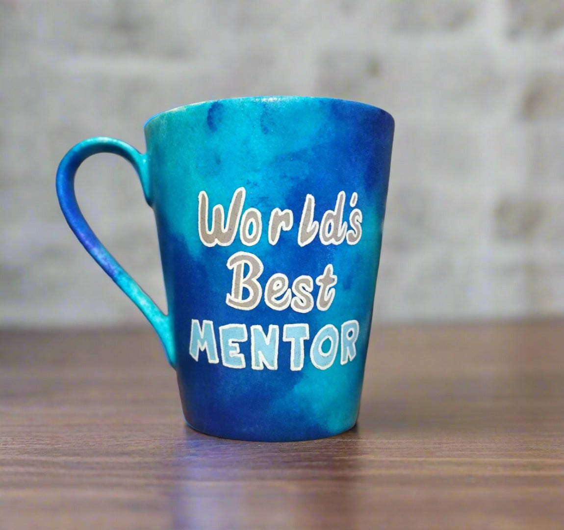 A Blue hand apinted mug with the words "Worlds best Mentor"