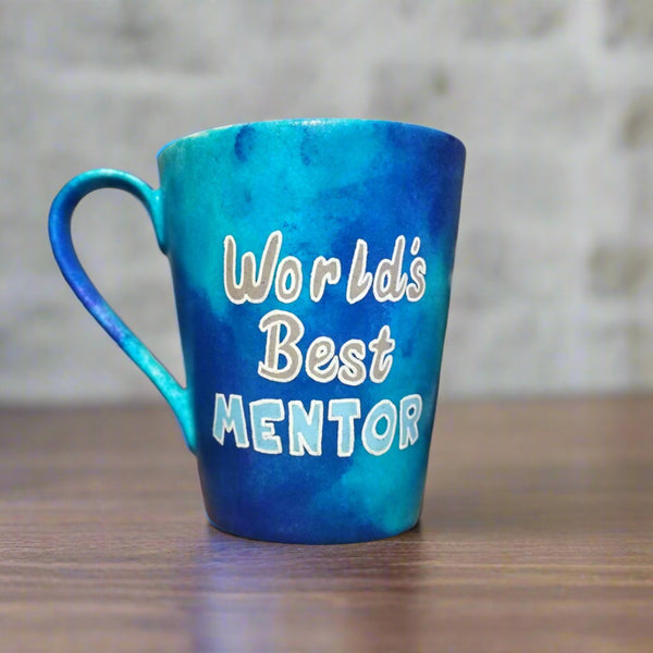 A Blue hand apinted mug with the words "Worlds best Mentor"