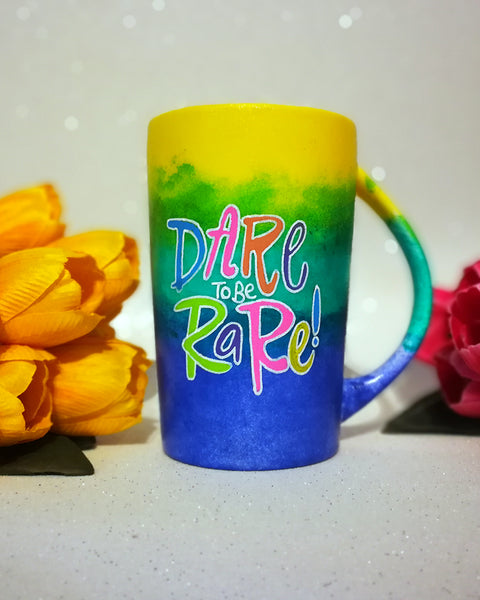 A gradient colored mug (from top yellow then green then ming blue) with the words "Dare to be Rare)