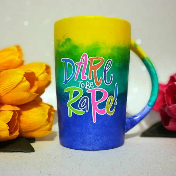 A gradient colored mug (from top yellow then green then ming blue) with the words "Dare to be Rare)