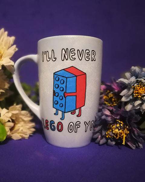 A baby blue hand-painted mug with the words "I'll never" and below it two lego pieces hugging each other and the below it the words "LEGO of you"