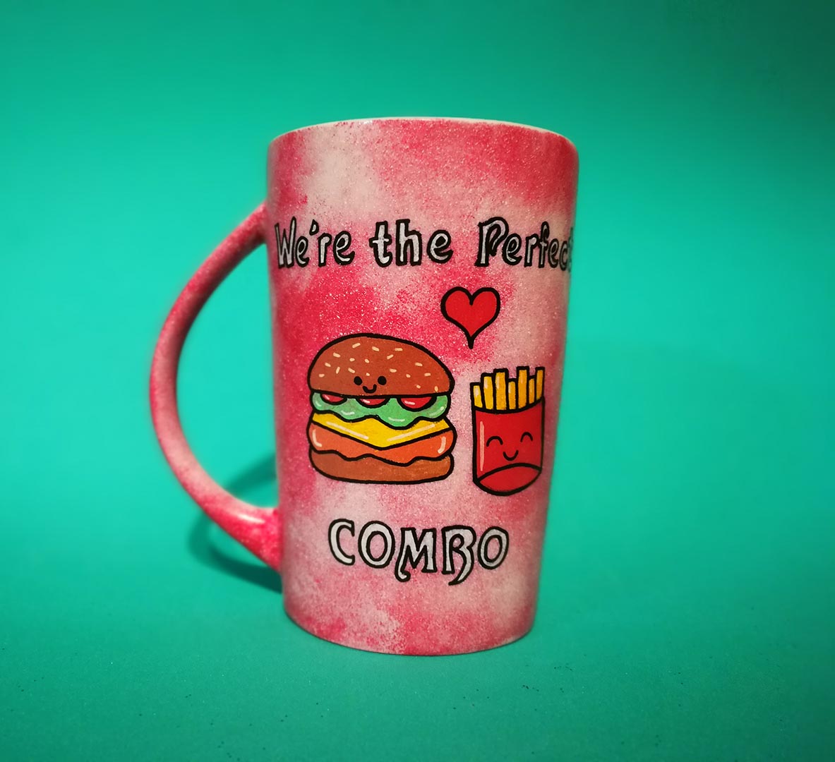 A hand-painted red galaxy mug with the words "we're the perfect combo"