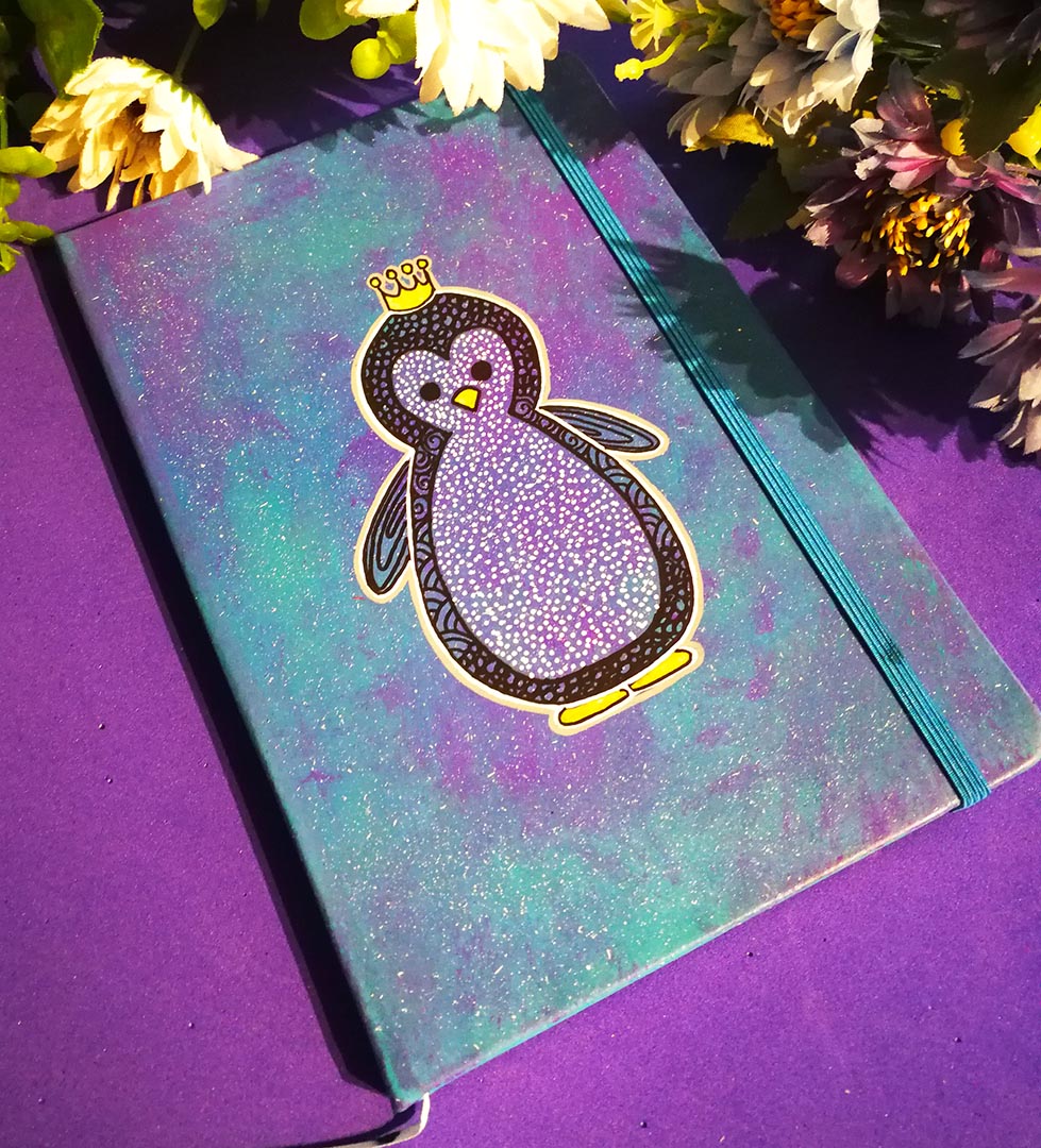 a Blue galaxy hand painted notebook with a penguin painted on it