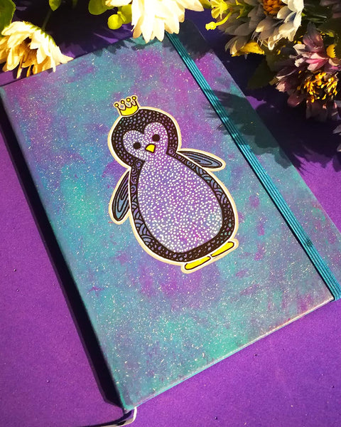 a Blue galaxy hand painted notebook with a penguin painted on it