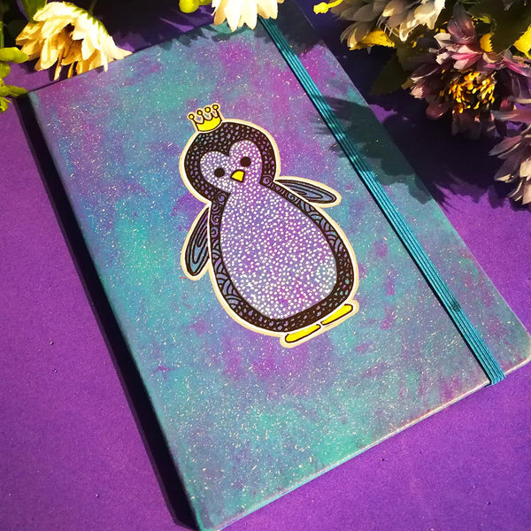 a Blue galaxy hand painted notebook with a penguin painted on it