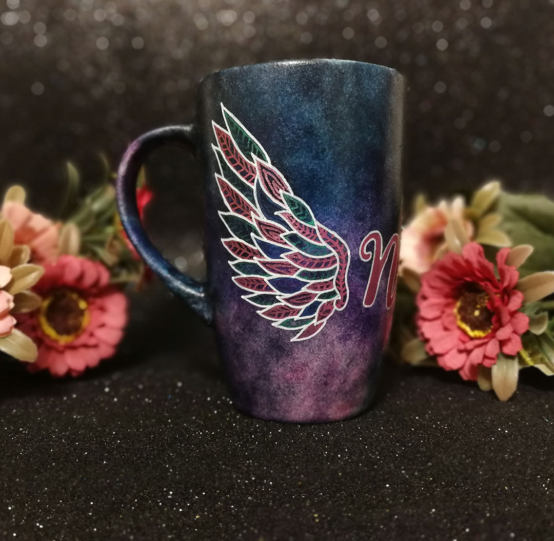 A Dark Sky hand painted mug with a wing drawn on one side 