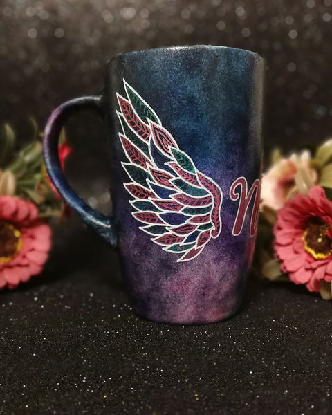 A Dark Sky hand painted mug with a wing drawn on one side 