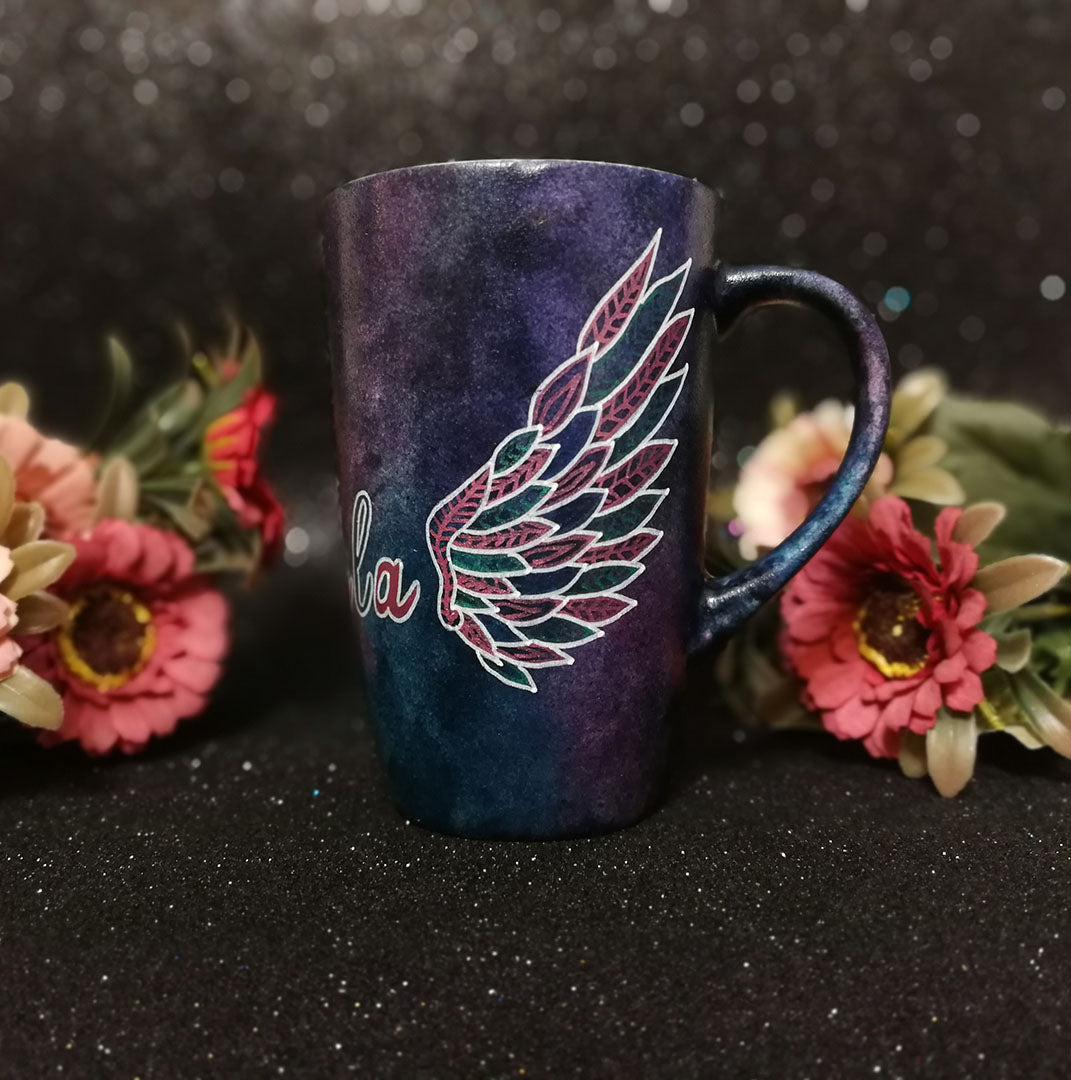 A Dark Sky hand painted mug with a wing drawn on one side 