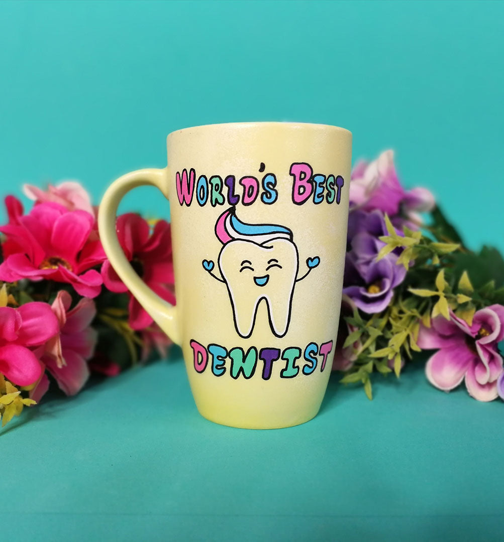 a pastel yellow hand painted mug with wht words "world's best Dentist " and a tooth smiling with toothpaste on it