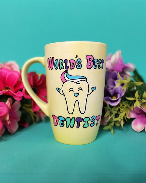 a pastel yellow hand painted mug with wht words "world's best Dentist " and a tooth smiling with toothpaste on it