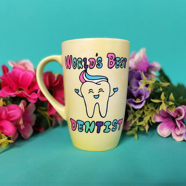 a pastel yellow hand painted mug with wht words "world's best Dentist " and a tooth smiling with toothpaste on it