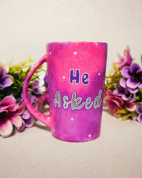 A hand-painted pink galaxy mug with the words "He asked" and white dots scattered all over