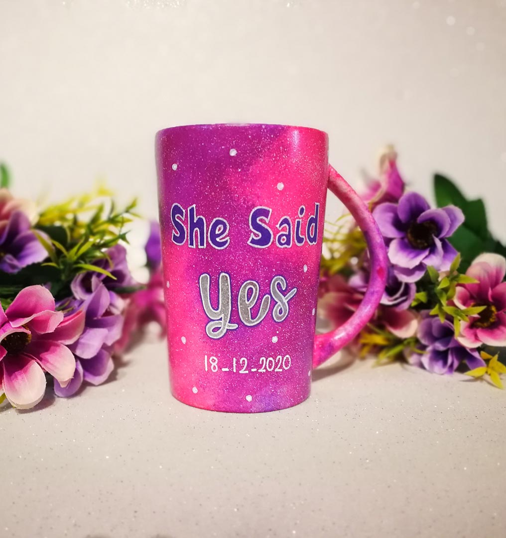 A hand-painted pink galaxy mug with the words "she said yes" and under it the date "18-12-2020" with white dots scattered all over