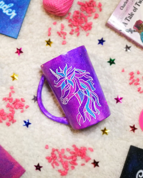 A purple galaxy hand painted mug with a zentangle unicorn design on it