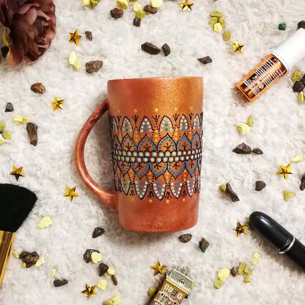 A Copper hand painted mug with patterns in the middle using black outliner and baby blue ,blue and gold dot art