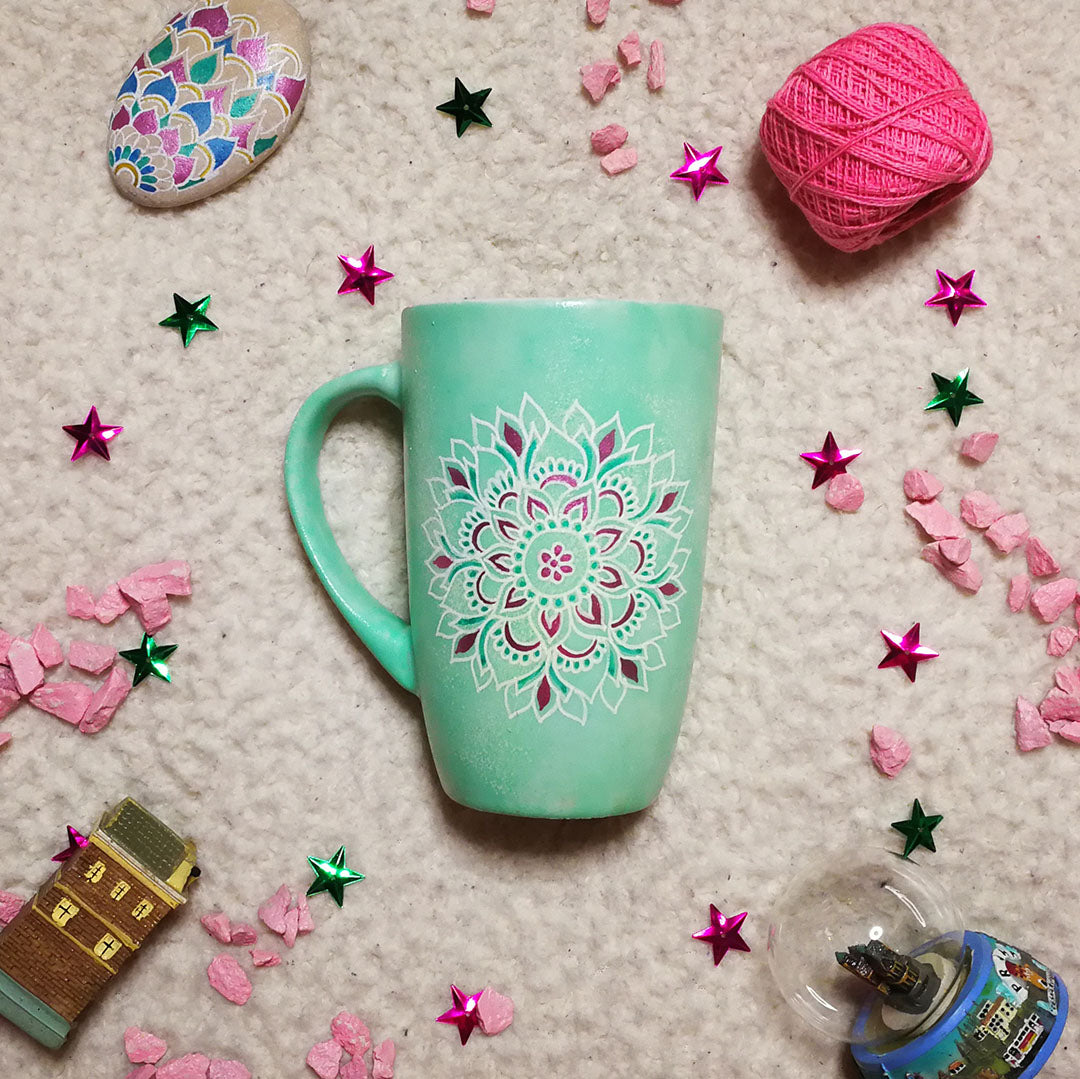 A Mint Green Hand Painted mug with a mandala painted in white in the center