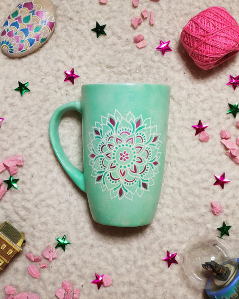 A Mint Green Hand Painted mug with a mandala painted in white in the center