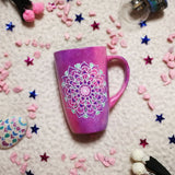 A Pink galaxy hand paitned mug with a mandala painted in the center with white