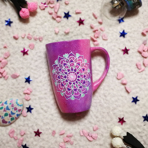 A Pink galaxy hand paitned mug with a mandala painted in the center with white