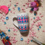 A White mug with patterns in pink and turquoise outlined with gold relief and dot art of white purple pink and turquoise.