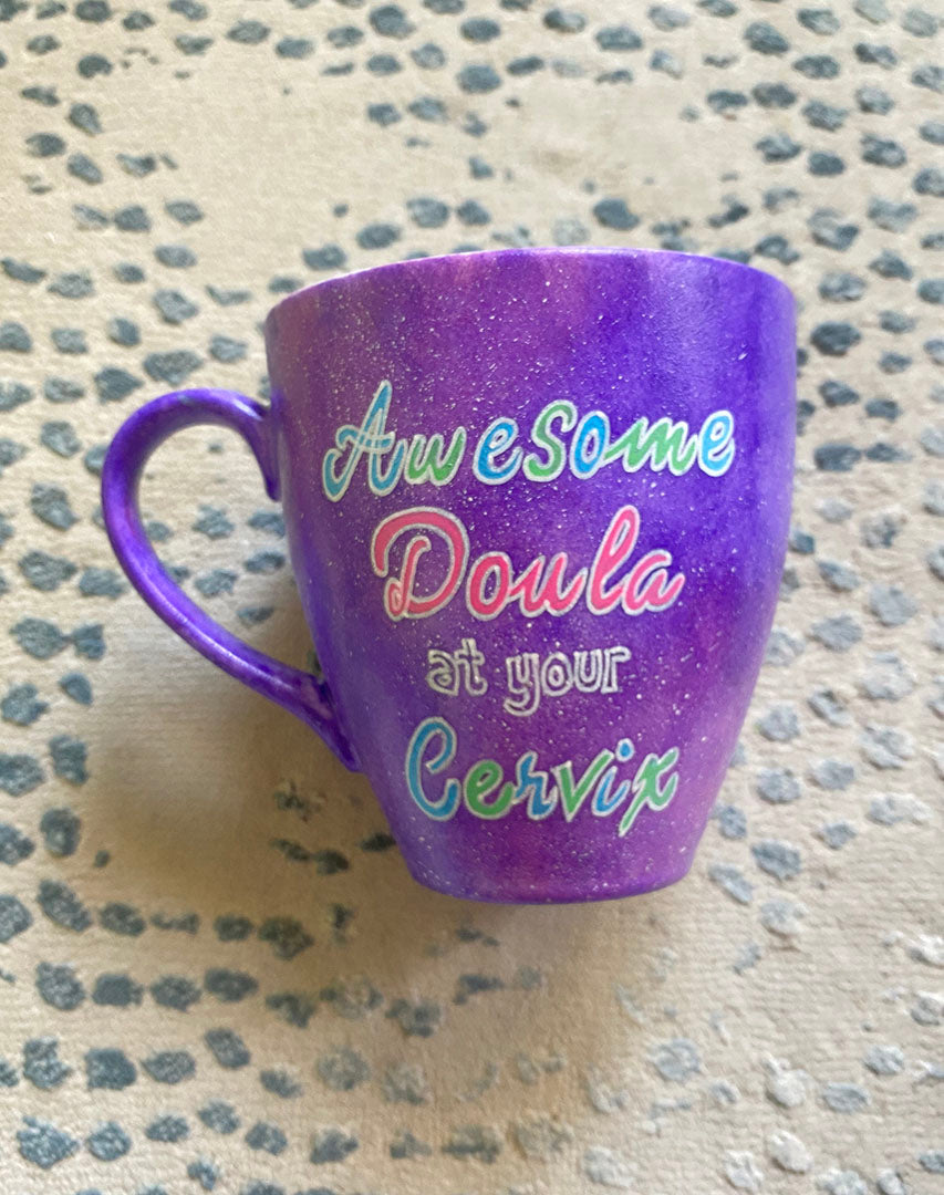 A Purple Galaxy hand painted mug with the words "Awesome Doula at your Cervix"