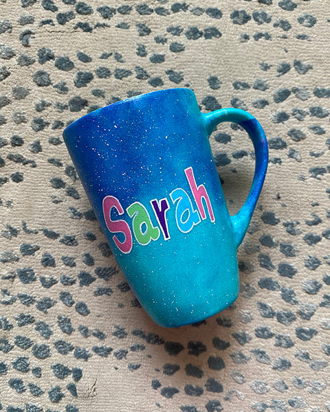 A Blue Galaxy Hand painted mug with the name "Sarah" 