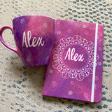 A Gift set of a mug and notebook in pink galaxy with the mug hacing the name alex and the notebook having the name alex in a mandala