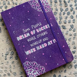 A Purple Galaxy Hand painted notebook with 2 small mandala drawn in white in the opposite corners and the quote written in the center 