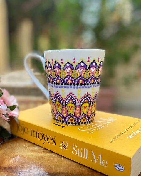 A white mug hand pa purple, yellow and pink outlined with black relief and dot art of purple , pink, yellow white and black