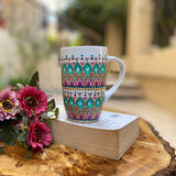 A white mug hand painted with patterns of fushia, taupe and green , all outlined with gold relief