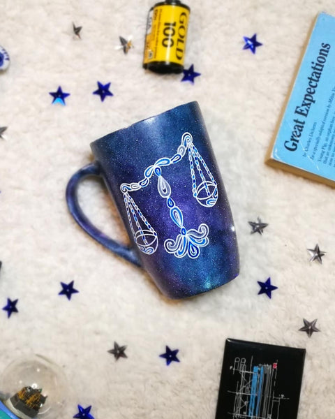 A black Galaxy hand painted mug with a libra design on it