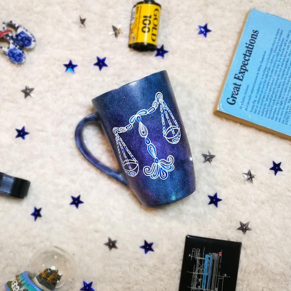 A black Galaxy hand painted mug with a libra design on it