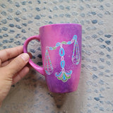 A Pink Galaxy hand painted mug with a libra design on it