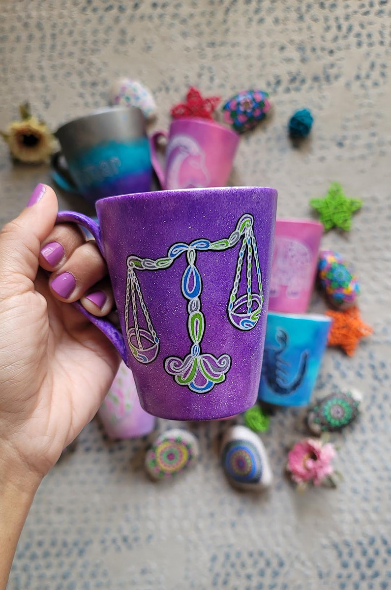 A Purple Galaxy hand painted mug with a libra design on it