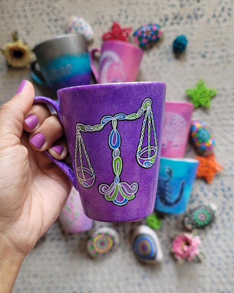 A Purple Galaxy hand painted mug with a libra design on it