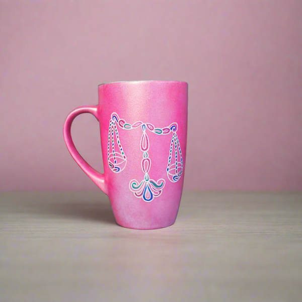 A Shimmery Pink hand painted mug with a libra design on it