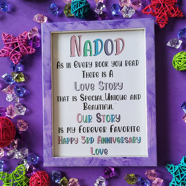 A Lilac Hand painted wooden frame with the following words written inside "Nadod, As in Every book you read there is a Love story that is special unique and beautiful, Our story is my forever favorite, happy 3rd anniversary"