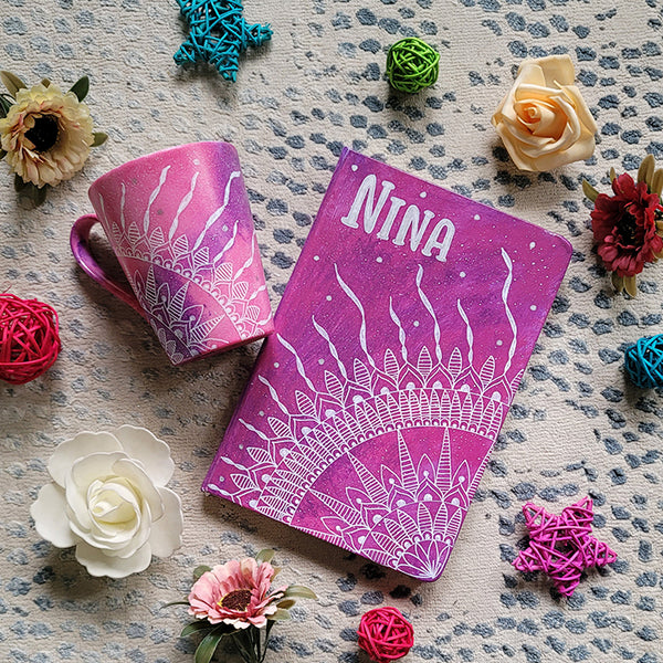 A Gift set of a matching mug and notebook both hand painted in pink galaxy color and have a corner mandala drawn in white. Both have the name Nina written on them