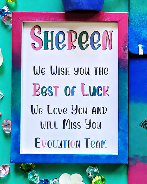 A Gradient hand painted wooden frame (Pink-green-blue) with the following words written inside "Shereen, We wish you the Best of Luck. We love you and will miss you, Evolution Team"