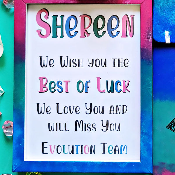 A Gradient hand painted wooden frame (Pink-green-blue) with the following words written inside "Shereen, We wish you the Best of Luck. We love you and will miss you, Evolution Team"