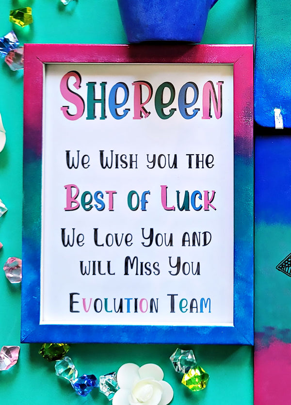 A Gradient hand painted wooden frame (Pink-green-blue) with the following words written inside "Shereen, We wish you the Best of Luck. We love you and will miss you, Evolution Team"