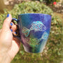 A Handpainted blue galaxy mug with a Pisces design on it