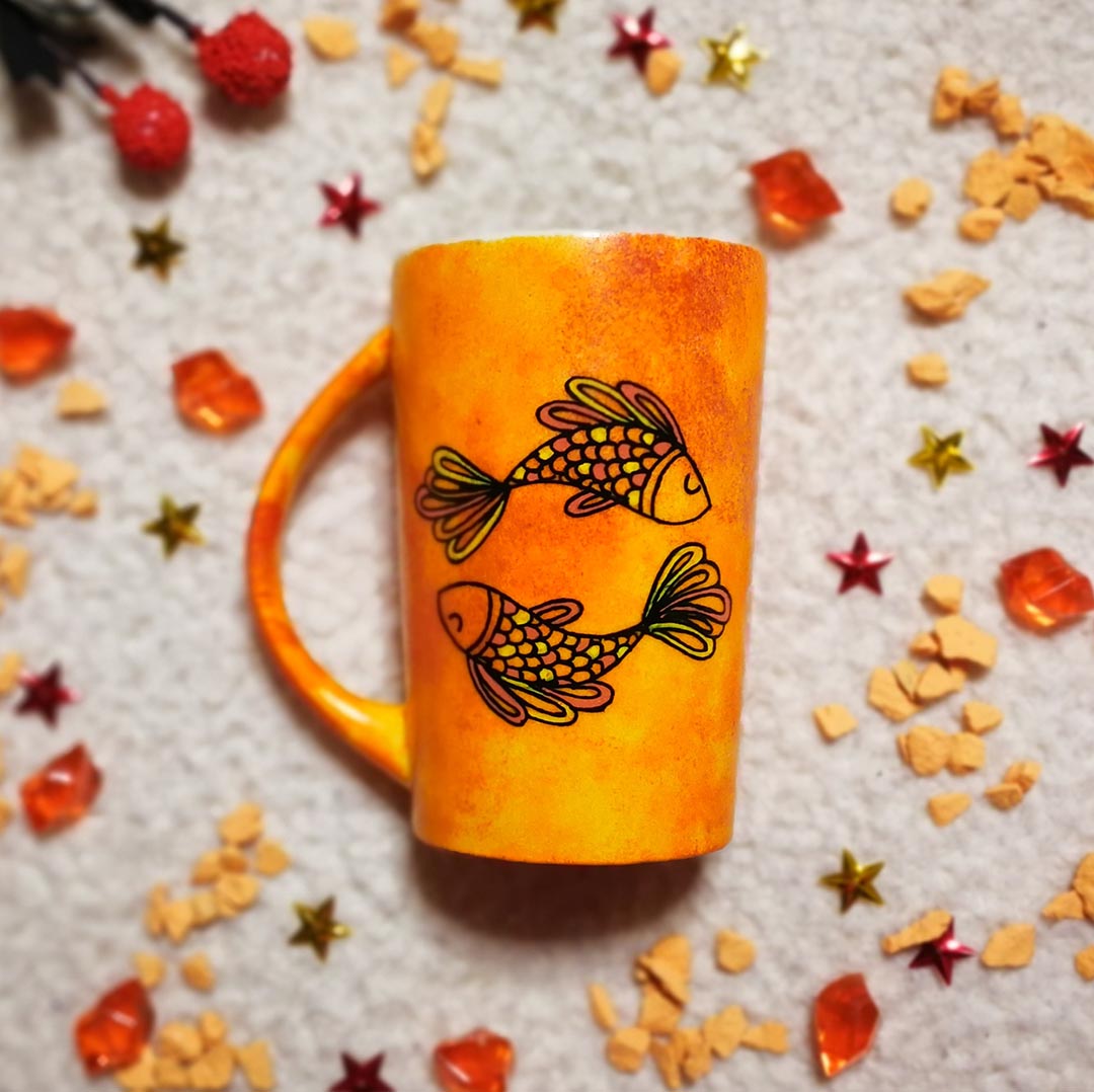 A Handpainted Orange mug with a Pisces design on it