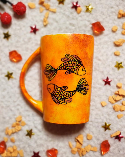 A Handpainted Orange mug with a Pisces design on it