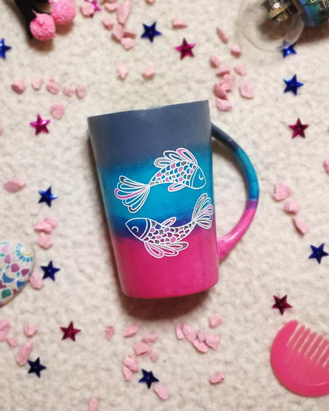 A Handpainted degradeh (grey-blue-pink) mug with a Pisces design on it