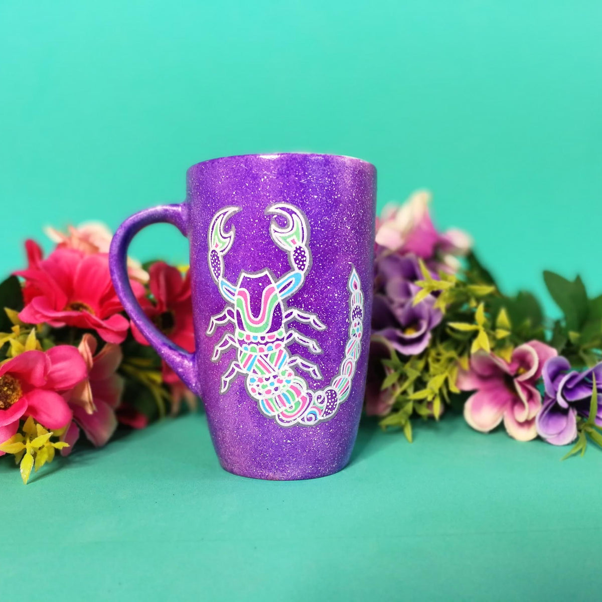 A Purple Galaxy Hand painted Mug With a Scorpio Design on it in Black and colored in pinks, greens and blues