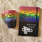 A hand painted Mug and notebook with the top half painted in rainbow and the bottom in dark galaxy, with the words on the rainbow written 